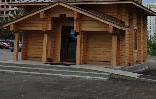 Крыльцо деревянного храма со ступенями и стеклянной входной дверью, без людей